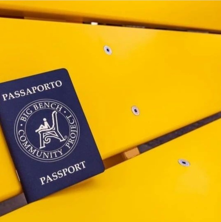 Il passaporto del Big Bench Community Project appoggiato su una panchina gialla.
