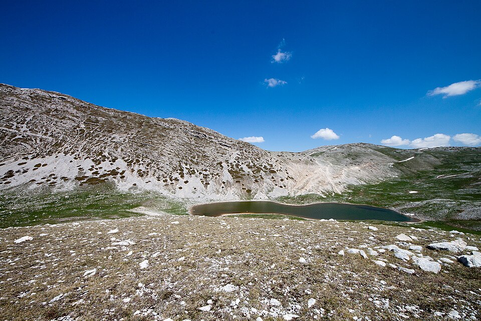 Il Lago della Duchessa ai piedi di pendii rocciosi, tra prati e pietre.