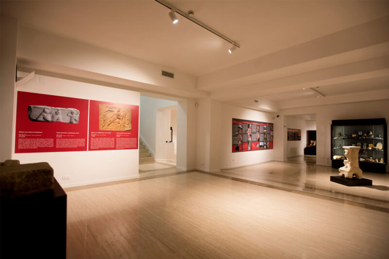 Una sala del museo con pannelli rossi, reperti e vetrine espositive.