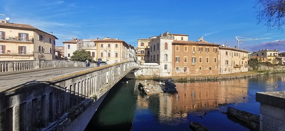 Un ponte sul fiume a Rieti, con gli edifici del centro storico lungo la riva.