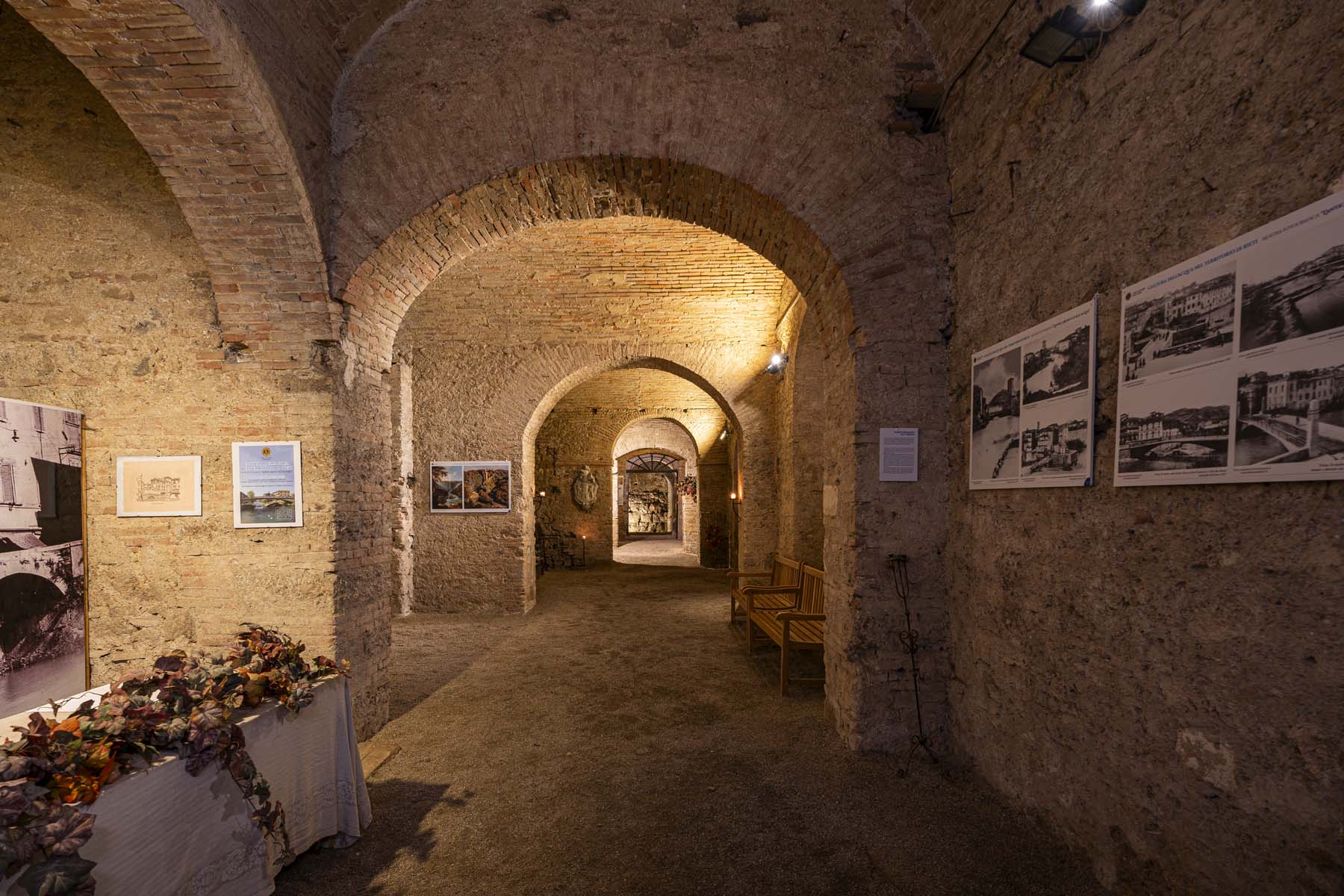 Un corridoio con volte in muratura e pannelli fotografici alle pareti.
